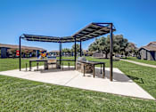 Thumbnail 22 of 46 - a picnic shelter with a firepit at the whispering winds apartments in pearland, tx