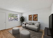 Thumbnail 2 of 26 - A living room with a grey couch, ottoman, and a television.