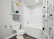Thumbnail 33 of 70 - A white toilet is in a bathroom with a patterned shower curtain.