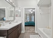 Thumbnail 18 of 40 - A bathroom with a white tub and a bed in the background.