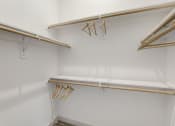 Thumbnail 20 of 37 - a walk in closet with white walls and wooden racks