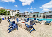 Thumbnail 22 of 36 - A poolside area with blue chairs and a table.