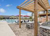 Thumbnail 15 of 29 - A wooden pergola over a patio with a pool in the background.