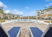 Thumbnail 12 of 29 - A swimming pool surrounded by a stone patio and lounge chairs.