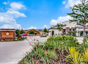 Thumbnail 36 of 36 - Landscaped entry feature beside driveway with community buildings in the background.