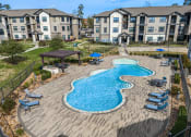 Thumbnail 23 of 35 - an aerial view of an outdoor pool with lounge chairs and umbrellas in front