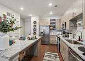 Thumbnail 1 of 31 - A kitchen with a granite countertop and stainless steel appliances.