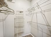 Thumbnail 13 of 27 - A white closet with metal racks and hangers.