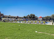 Thumbnail 18 of 46 - a fenced in grassy area with a playground in the background