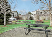 Thumbnail 40 of 48 - A black picnic table is in the foreground of a grassy area with a house in the background.
