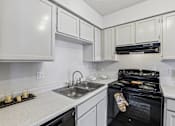 Thumbnail 5 of 26 - A kitchen with white cabinets and a black oven.