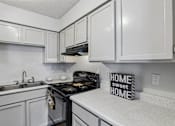Thumbnail 4 of 26 - A kitchen with white cabinets and a black stove top.