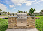 Thumbnail 25 of 33 - A brick outdoor kitchen with a grill and sink.