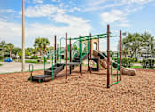 Thumbnail 27 of 33 - A playground with a green slide and a brown sandy ground.