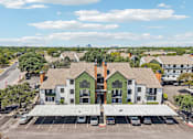Thumbnail 33 of 37 - A green and white building with a parking lot in front.