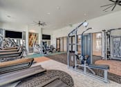 Thumbnail 25 of 30 - A gym with a variety of equipment including treadmills, weights, and a bench press.