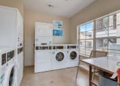 Thumbnail 28 of 44 - a laundry room with washer and dryer and a table with chairs
