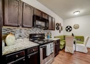 Thumbnail 6 of 42 - a kitchen with a stove top oven next to a table with a green couch in the background