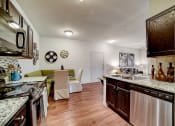 Thumbnail 4 of 42 - a kitchen and living room with white walls and wood flooring