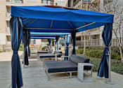 Thumbnail 24 of 49 - A blue canopy with curtains and a bench underneath it.
