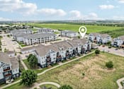 Thumbnail 69 of 70 - A bird's eye view of a residential area with apartment buildings and a large open field.