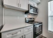 Thumbnail 1 of 21 - a kitchen with white cabinets and a stove and a microwave