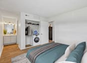 Thumbnail 8 of 26 - A bedroom with a bed, a washing machine, and a wardrobe.