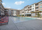Thumbnail 21 of 49 - A large swimming pool is surrounded by apartment buildings.