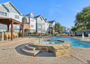 Thumbnail 58 of 70 - A pool area with a hot tub and a fountain in front of apartment buildings.
