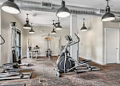 Thumbnail 16 of 32 - A gym with a variety of equipment including a stationary bike, treadmill, and weights.