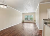Thumbnail 6 of 32 - A spacious room with wooden floors and a ceiling fan.