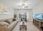 Thumbnail 1 of 40 - A living room with a couch, a coffee table, a television, and a painting on the wall.