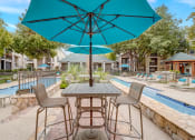 Thumbnail 29 of 44 - a patio with tables and umbrellas next to a swimming pool