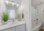 Thumbnail 9 of 26 - A white bathroom with a sink, mirror, and bathtub.