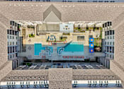 Thumbnail 42 of 49 - A top-down view of a building with a pool and a large open area with people sitting on chairs.
