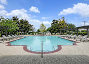 Thumbnail 18 of 32 - A large pool surrounded by lounge chairs and trees.