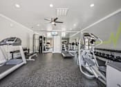 Thumbnail 26 of 45 - A gym with treadmills, elliptical machines, and weights.