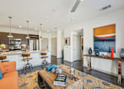Thumbnail 1 of 49 - A living room with a kitchen area in the background.