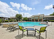 Thumbnail 19 of 32 - A pool with chairs around it and a building in the background.