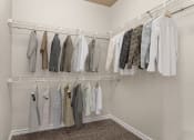 Thumbnail 5 of 28 - a walk in closet with white walls and a white rod with clothes hanging on it