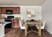 Thumbnail 3 of 28 - a dining room with a table and chairs and a kitchen in the background