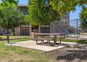 Thumbnail 18 of 28 - a picnic table in a park with a playground in the background