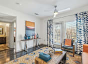 Thumbnail 2 of 49 - A living room with a rug, a chair, a table, and a painting on the wall.
