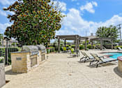 Thumbnail 25 of 32 - A pool area with a grill and lounge chairs.