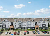 Thumbnail 37 of 70 - A large apartment complex with a parking lot in front.