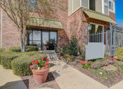 Thumbnail 36 of 42 - a sidewalk in front of a brick building with flowers and bushes