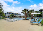Thumbnail 34 of 42 - a large pool with lounge chairs and umbrellas at the enclave at woodbridge apartments in