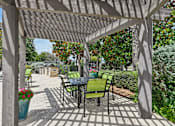 Thumbnail 22 of 32 - A patio with a table and chairs under a pergola.