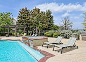 Thumbnail 24 of 32 - A pool with a red brick border and striped lounge chairs.