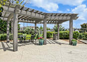 Thumbnail 26 of 32 - A pergola with chairs and potted plants.